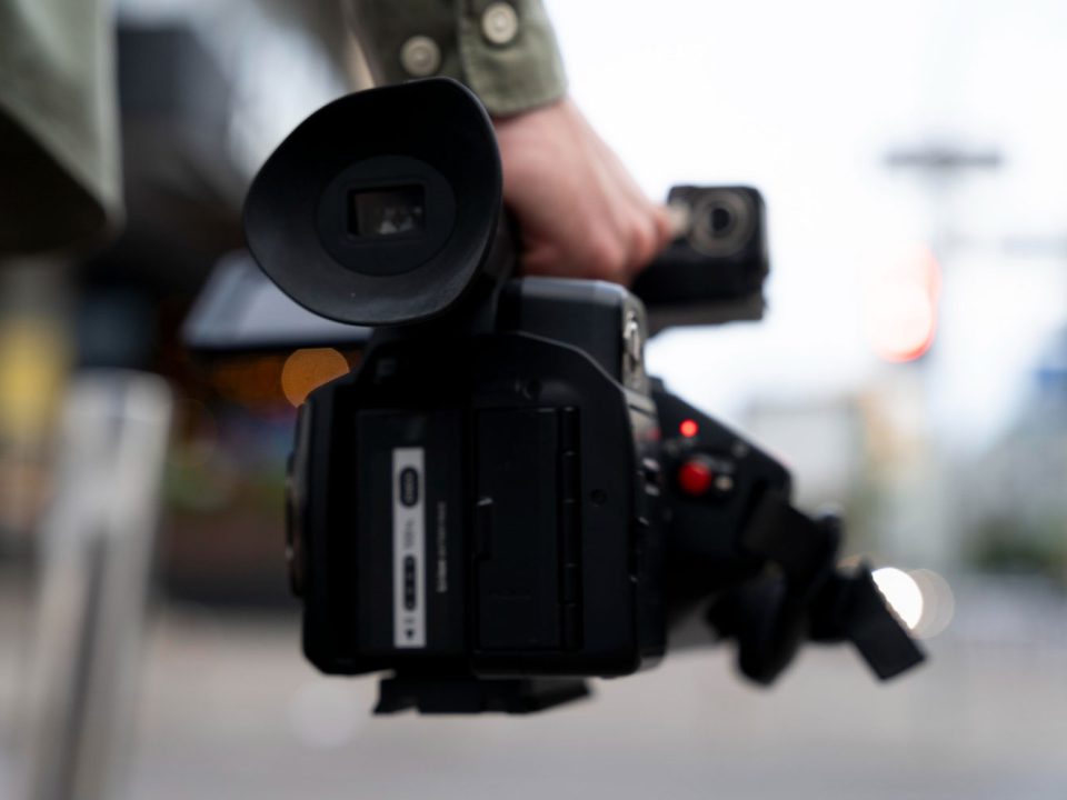 دوربین فیلمبرداری در دست مرد در حال رفتن برای تهیه گزارش ویدیویی یا تصویری